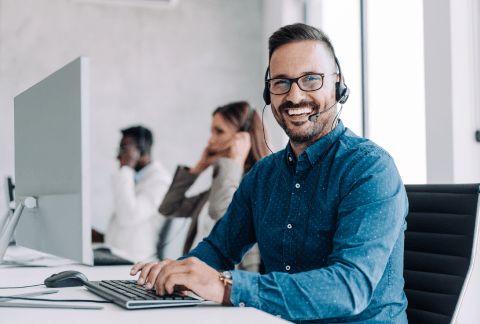 Man at computer with headset on smiling