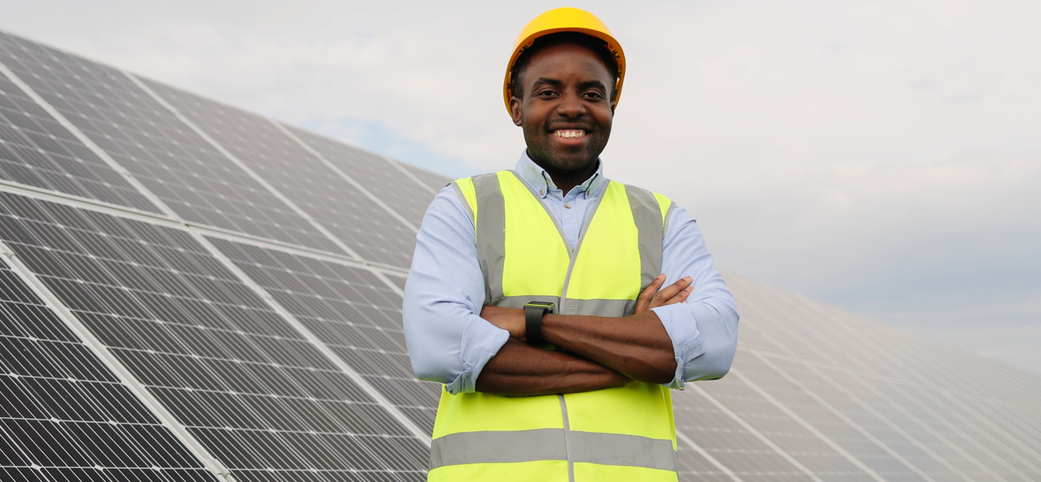 Man with hard hat and safety vest standing in front of solar panels